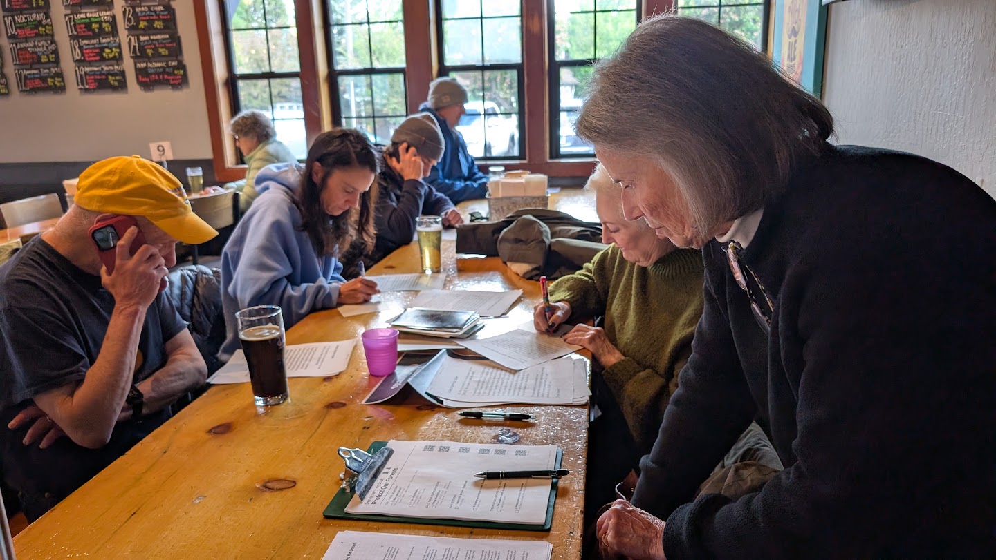 Neighbors gathered around a long table at a brewery, making calls to Congress and writing letters